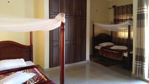 Une chambre à coucher avec un lit à baldaquin, une armoire, un plus petit lit et une salle de bain avec un rideau de douche.