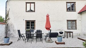 An outdoor patio with a table and chairs, a grill, and potted plants.