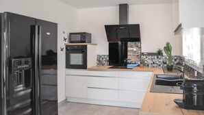 Eine moderne Küche mit einem schwarzen Kühlschrank, einer Mikrowelle, einem Backofen und einer Kaffeemaschine.