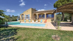 A two-story house with a swimming pool, a covered patio, and a stone facade.