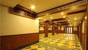 A spacious hallway with patterned flooring, wooden paneling, and recessed lighting. - Nahar Manchester Inn (Coimbatore)
