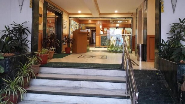A hotel reception area with a marble staircase leading up to a reception desk. - Nahar Manchester Inn (Coimbatore)