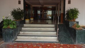 A hotel entrance with marble steps, a tiled floor, and potted plants on either side. - Nahar Manchester Inn (Coimbatore)
