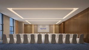 Un salón de conferencias con filas de sillas, una pantalla grande mostrando 'Kyriad' y un diseño de techo moderno.