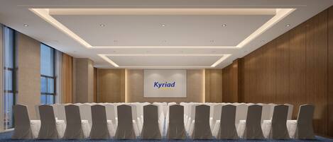 A conference room with rows of chairs, a large screen displaying 'Kyriad', and a modern ceiling design.