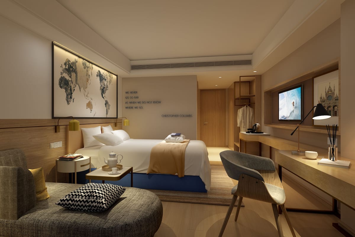 A modern hotel room with a large bed, a desk, a chair, and a television.