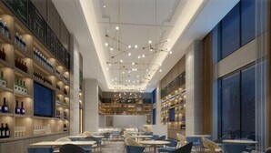 Un restaurante moderno con un comedor central, techos altos y diversas opciones de asientos.