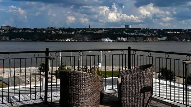 En balkon med fletmøbler med udsigt over en byudsigt ved vandet.