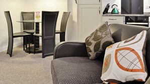 Un espace de vie compact comprenant une table à manger, des chaises, un canapé et un coin cuisine.