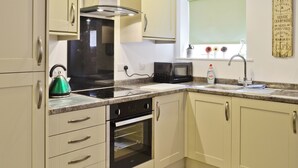 Une cuisine équipée d’une cuisinière, d’un four, d’un four à micro-ondes et d’une fenêtre donnant sur l’extérieur.