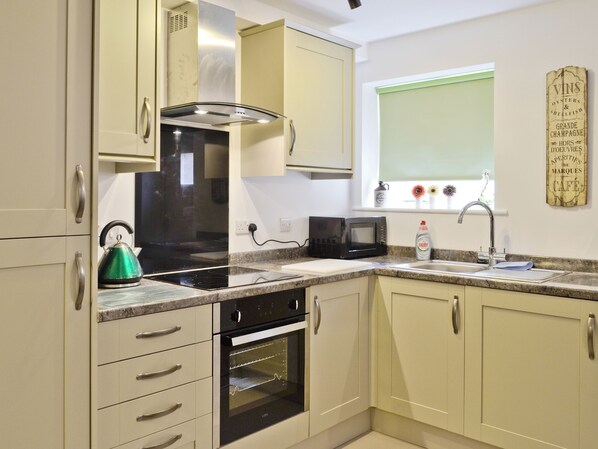 A kitchen with a stove, oven, microwave, and a window with a view of the outside.