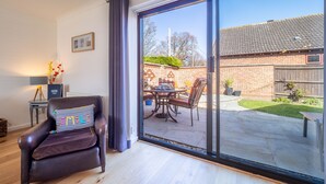 Ein modernes Wohnzimmer mit Ledersessel und Glastür zu einer Terrasse mit Gartenmöbeln.