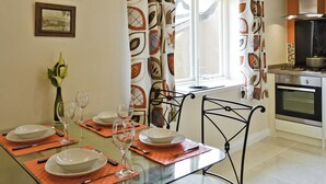 A dining area with a glass table set for four, chairs, and a vase with flowers. - 1 bedroom accommodation in Llandudno (Llandudno)