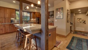 Una cocina amplia con armarios de madera, encimera de granito y una isla grande con taburetes.
