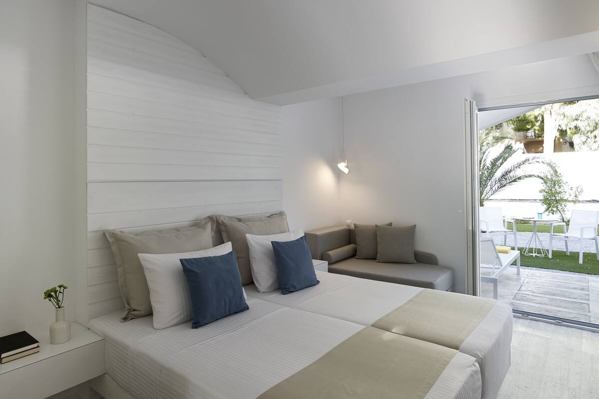 Une chambre moderne avec un grand lit, un canapé et une vue sur une terrasse extérieure.