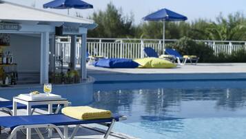 A poolside area with lounge chairs, a bar, and umbrellas.