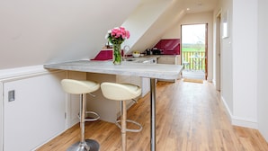 A modern kitchen with a marble countertop, two bar stools, and a vase of flowers. - 1 bedroom accommodation in Near The New Forest (Near The New Forest)