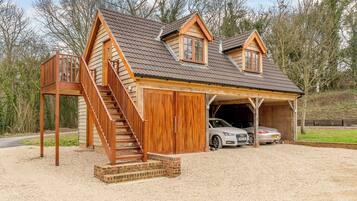 Une cabane en bois avec un garage, un escalier et deux voitures garées à l’intérieur.