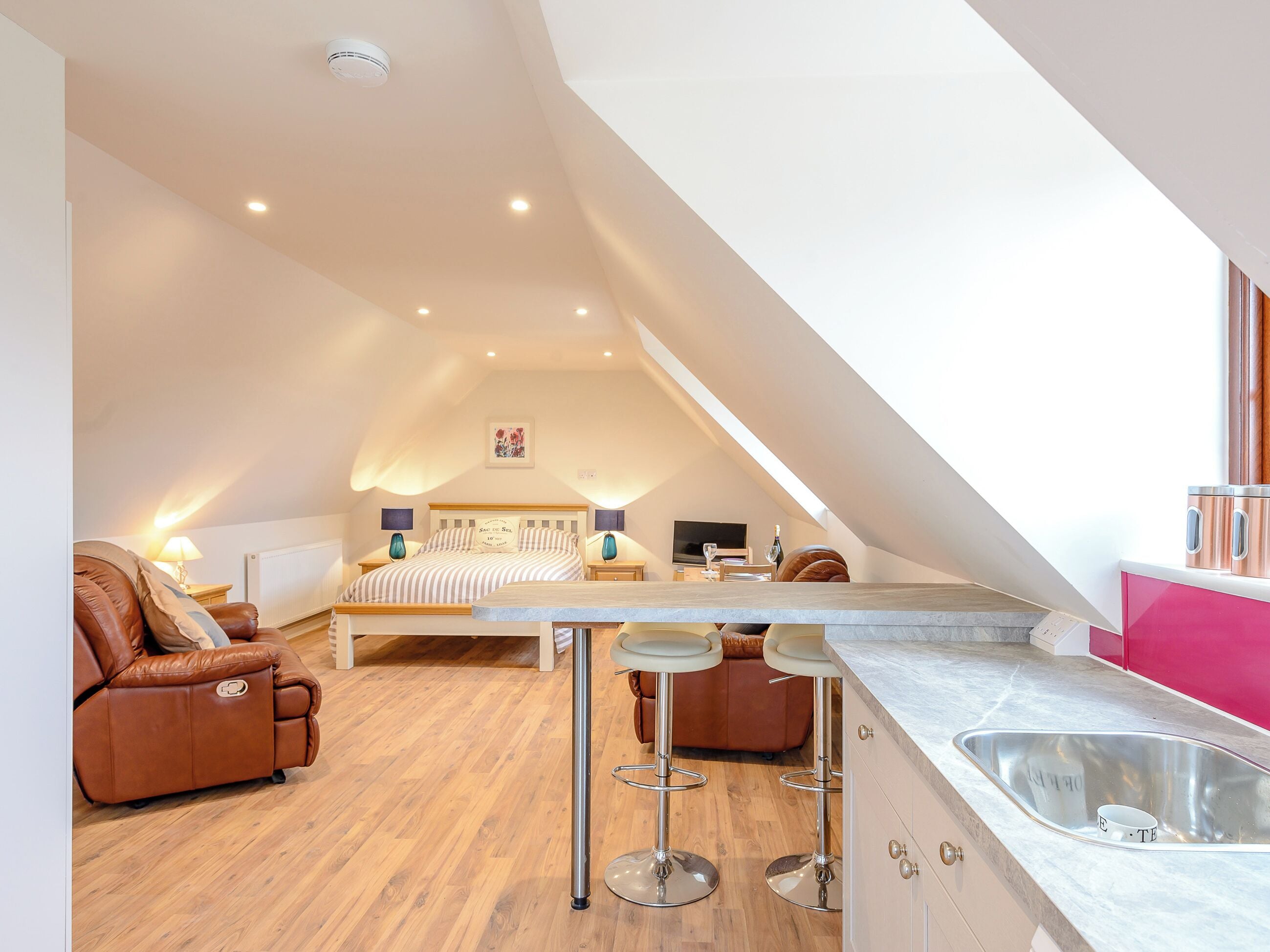 Une chambre de style loft moderne, dotée d’un grand lit, d’un coin salon et d’une kitchenette.