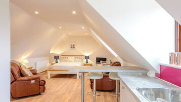 Une chambre de style loft moderne, dotée d’un grand lit, d’un coin salon et d’une kitchenette.