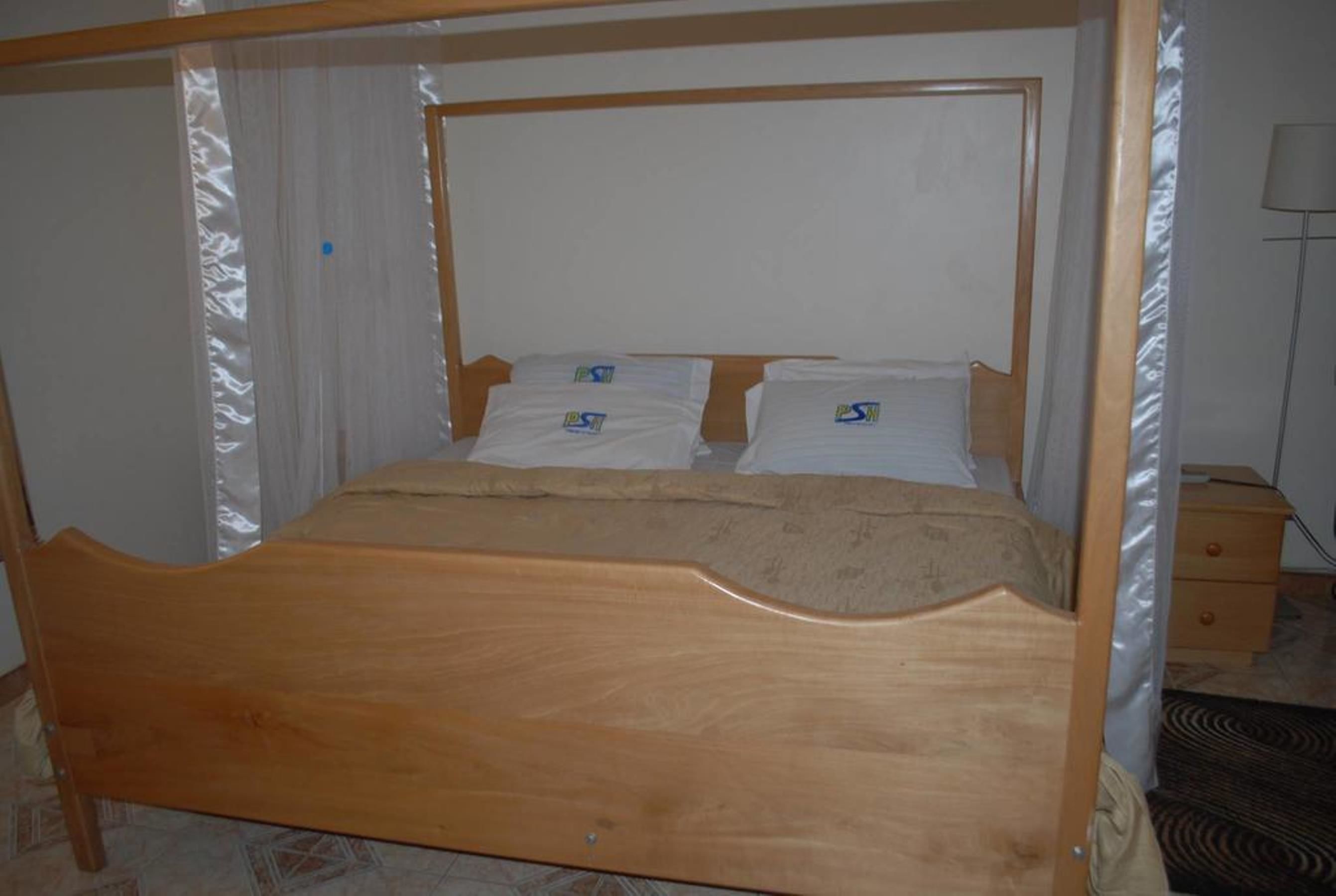Una cama de madera con dosel, una mesita de noche y una lámpara.
