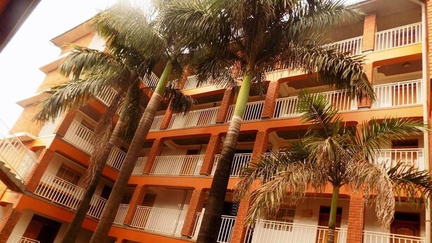 A multi-story building with balconies and palm trees. - Palm Springs Hotel (Masaka)