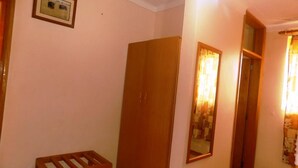 A hallway with a wooden door, a small wooden stool, and a mirror on the wall. - Palm Springs Hotel (Masaka)