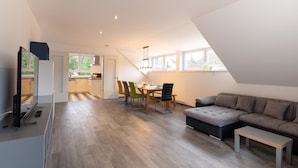 Un loft moderno con comedor, kitchenette y sala de estar con sofá y televisor.