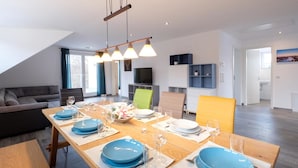 Un comedor moderno con una mesa de madera dispuesta para cuatro, platos azules y una araña.