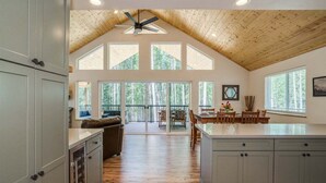 A spacious kitchen with a high ceiling, large windows, and a dining area with a view.