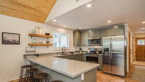 A modern kitchen with a large island, stainless steel appliances, and wooden accents.