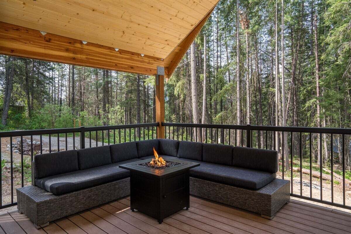 Un espace extérieur aménagé, partiellement abrité, avec un foyer, le tout entouré d’une forêt.