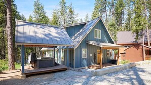 A cabin with a covered porch, a hot tub, and a deck area.