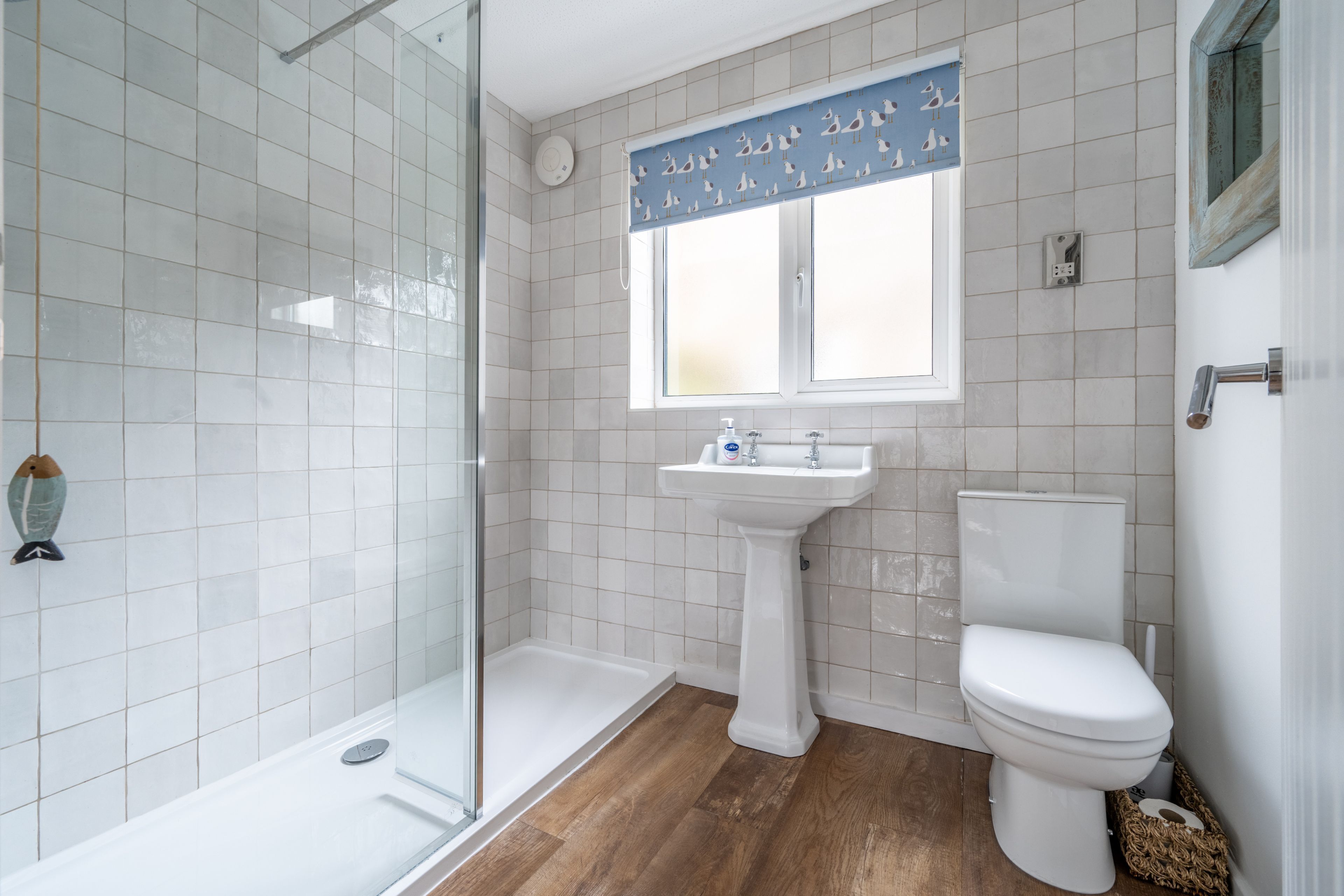 A bathroom with a glass shower enclosure, a pedestal sink, and a toilet.
