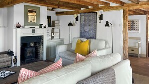 Uma sala de estar com lareira, sofá, abajur e um quadro na parede.