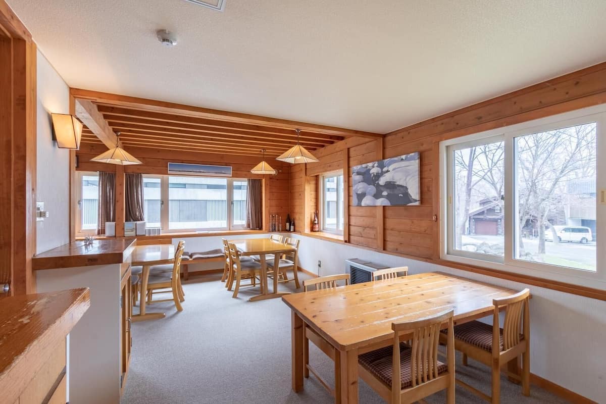 Un interior de madera con comedor, ventanas amplias y vistas al exterior.