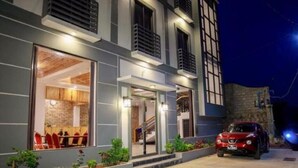 A modern building with a glass facade, a visible staircase, and a red car parked outside. - Sky Motel Kalaw (Kalaw)