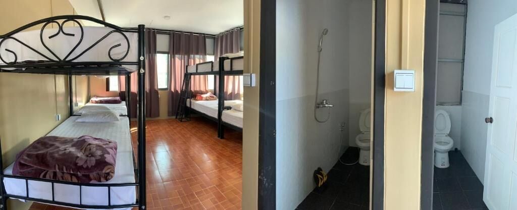 A dormitory room with bunk beds, a bathroom with a shower, and a toilet.