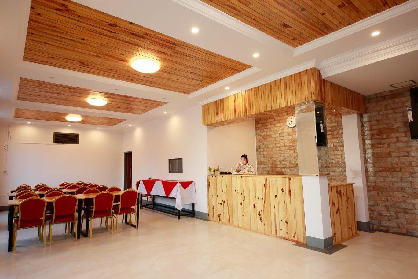 A conference room with wooden ceiling beams, a reception desk, and a stone wall.