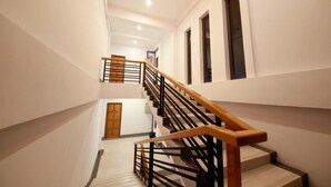 A multi-level interior with a wooden staircase, white walls, and a ceiling light fixture. - Sky Motel Kalaw (Kalaw)
