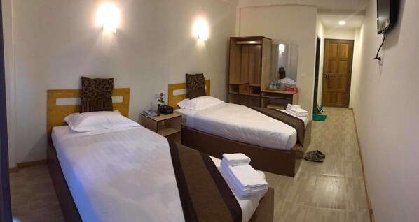 A hotel room with two beds, a wardrobe, a mirror, and a TV mounted on the wall.