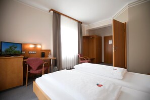 A hotel room with a bed, a desk, a chair, a television, and a wardrobe. - Neumaiers Hirsch Gasthof & Landhotel (Weissenhorn)