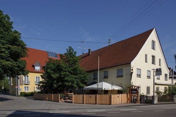 A hotel with a red roof, a yellow building, and a white building with a sign. - Neumaiers Hirsch Gasthof & Landhotel (Weissenhorn)