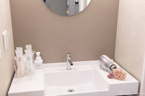 A bathroom with a white sink, a mirror, and toiletries. - Framboise KYOTO Hotel de charme (Kyoto)