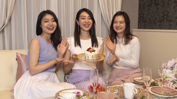 Three people seated at a table with a cake, surrounded by floral decorations and a patterned wall. - Framboise KYOTO Hotel de charme (Kyoto)