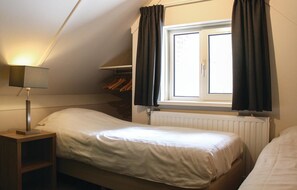 A bedroom with a single bed, a bedside table with a lamp, a window with curtains, and a radiator. - 3 bedroom amazing home in Ommen (Ommen)