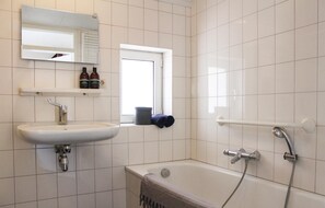 A bathroom with a sink, mirror, and bathtub. There are two bottles on the wall and a window above the sink. - 3 bedroom amazing home in Ommen (Ommen)