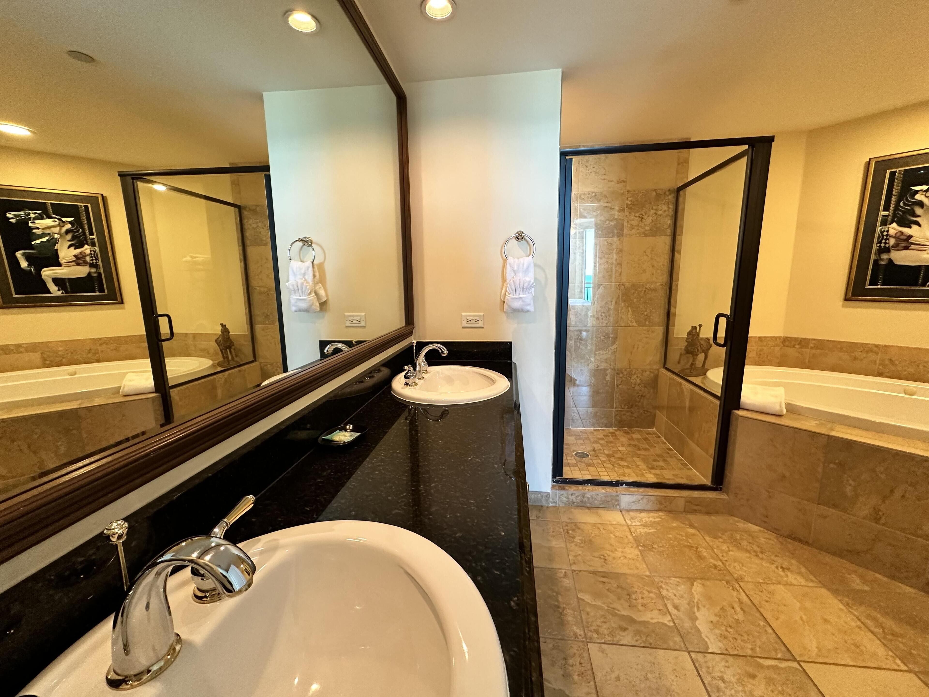 A modern bathroom with two sinks, a large mirror, and a glass-enclosed shower.