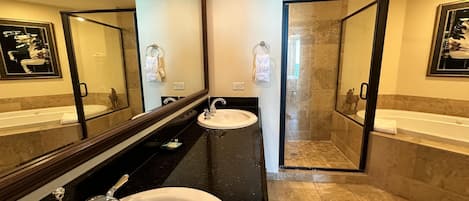 A modern bathroom with two sinks, a large mirror, and a glass-enclosed shower.