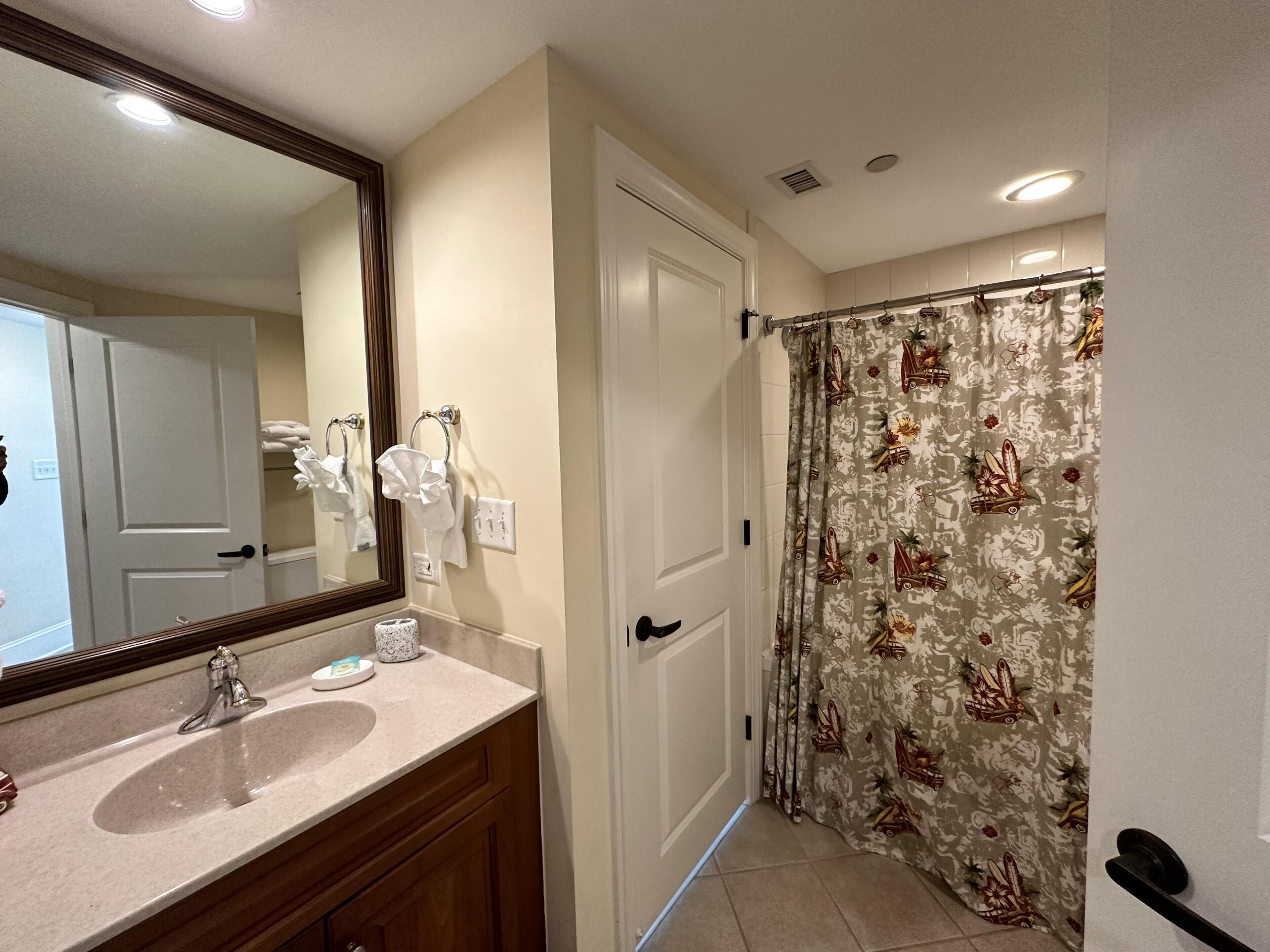 Une salle de bain équipée d’un lavabo, d’un miroir, d’un porte-serviettes et d’un rideau de douche.